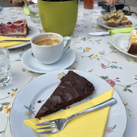 Kaffeepause: Schokokuchen und Milchkaffee auf geblümter Tischdecke