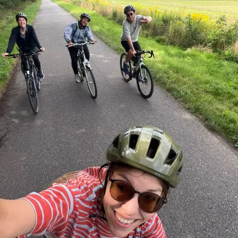 Selfie aus dem Sattel, dahinter drei Radfahrende auf dem Feldweg